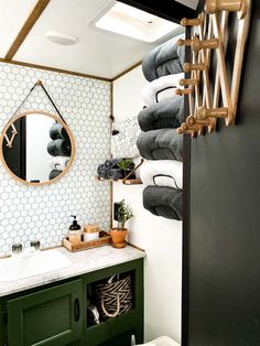 a bathroom with green cabinetry and white tiles on the wall, along with towels hanging from hooks