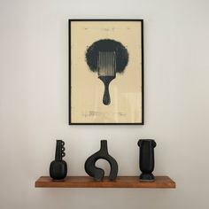 three vases sit on a shelf in front of a framed art piece with a comb