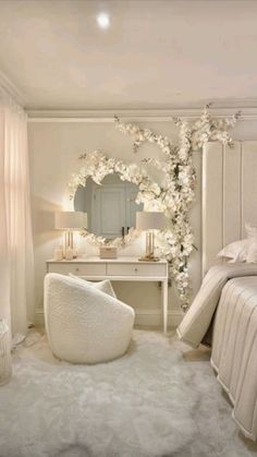 a bedroom with white furniture and flowers on the wall above the bed, along with a round mirror