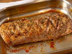 a piece of meat sitting on top of a metal pan filled with sauce and seasoning