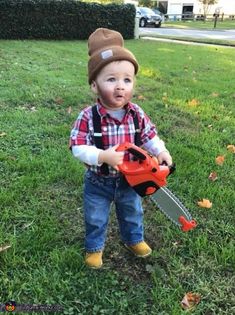 a toddler holding a chainsaw in the grass