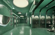 a green tiled bathroom with urinals and lights on the ceiling is pictured in this image