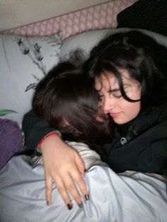 two women laying in bed hugging each other