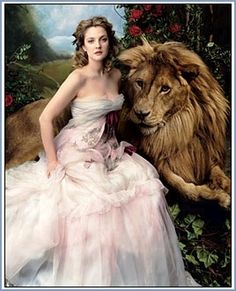 a woman in a white dress sitting next to a lion