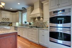 a large kitchen with white cabinets and stainless steel appliances