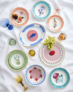 there are many plates on the table with flowers and fish painted on them, including one for each plate