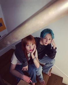 two young women sitting on the stairs with their hands to their face and looking at the camera