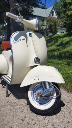 a white scooter parked on the side of a road next to a tree