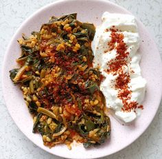 a white plate topped with rice and greens next to a bowl of yogurt