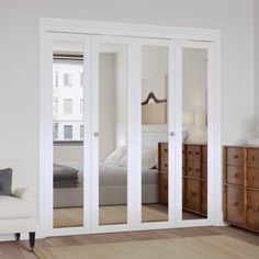 an empty bedroom with white furniture and mirrored doors