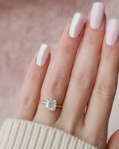 a woman's hand with pink and white manicured nails holding a diamond ring