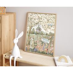 a white rabbit figurine sitting on top of a wooden bench next to a painting