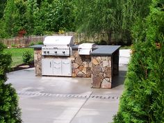 an outdoor kitchen with stone counter tops and grill