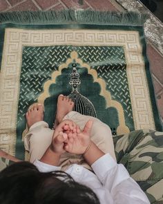 a woman laying on top of a green rug next to a person holding their feet