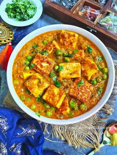 a bowl filled with tofu and peas on top of a table next to other foods