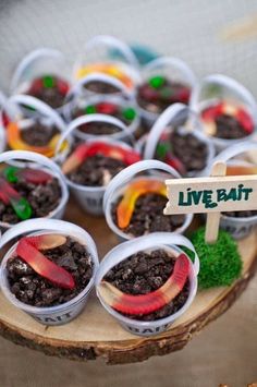 a table topped with plastic cups filled with dirt and veggies on top of it