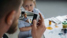 a man holding up a cell phone to take a photo with a child on the screen