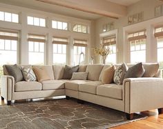 a living room filled with lots of furniture next to large windows on top of a hard wood floor