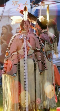 two people dressed in native clothing standing next to each other