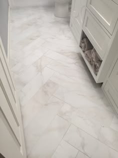 a bathroom with white marble flooring and cabinets in the shower area, along with a toilet