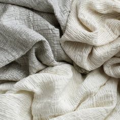 a pile of white and grey blankets sitting on top of each other