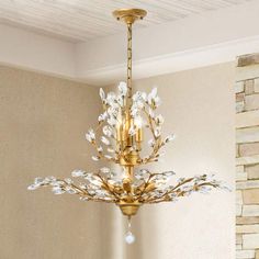 a gold chandelier with white flowers hanging from the ceiling in a living room