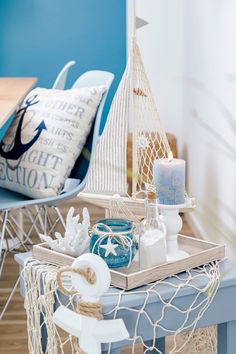 a blue table topped with a basket filled with items next to a chair and pillow