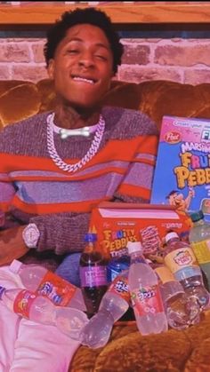 a young man sitting on a couch with bottles of water and other items in front of him