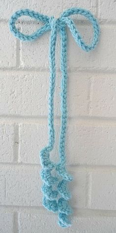 a blue crocheted tie hanging on a white brick wall