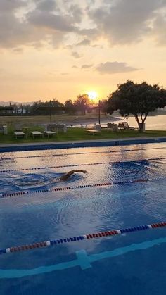 an empty swimming pool with the sun setting in the background