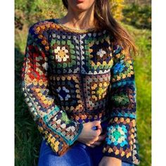 a woman wearing a multicolored crocheted sweater with flowers on the shoulders