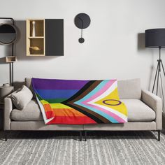 a couch with a colorful blanket on it in front of two lamps and a clock