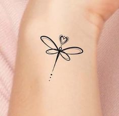 a small tattoo on the wrist of a woman with a heart shaped dragonfly design