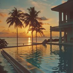 the sun is setting behind two palm trees near an empty swimming pool with no people in it