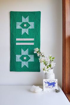 a vase filled with flowers next to a wall hanging