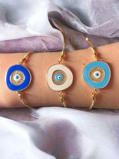 Gold Evil Eye Bracelets with colorful models. Length: 7 inches (18 cm) approx. Keep the evil eyes away from you with its eye-catching style. 👁️ Elevate your style with our captivating Evil Eye Bracelet! 💙 Crafted with the protective essence of Nazar Boncuk, this blue-eyed beauty is more than just jewelry; it's a symbol of charm and defense. The beaded design adds a touch of elegance, making it the perfect accessory for any occasion. Gift this unique Evil Eye Bangle on Valentine's Day or any special day to show her you care! 🎁✨ Note: This listing contains 1 piece bracelet. Please check for to see other models of bracelets: https://www.etsy.com/shop/EyeLikeItShop?ref=seller-platform-mcnav§ion_id=26188650 Multicolor Round Evil Eye Jewelry, Multicolor Round Bracelets As Gift, Multicolor Round Bracelets For Gifts, White Circular Jewelry For The Beach, Blue Metal Bracelets For Beach, Multicolor Evil Eye Bangle Bracelet Gift, Multicolor Evil Eye Bracelet Gift, Handmade Metal Evil Eye Bracelet, Multicolor Evil Eye Bracelets As Gift