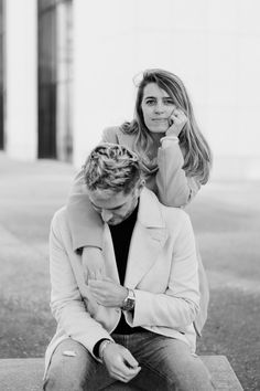 a woman sitting on the ground talking on a cell phone next to a man who is holding his head