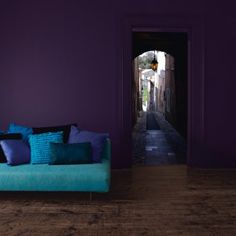 a living room with purple walls and blue pillows on the couch in front of it