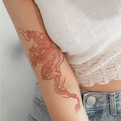 a woman's arm with a red dragon tattoo on the left side of her arm