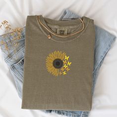 Embrace the beauty of summer with our Summer Sunflower Butterfly Shirt, crafted from 100% cotton and garment dyed for an ultra-soft, lived-in feel. This charming shirt features an intricately embroidered sunflower in full bloom, beautifully accented with delicate butterflies, making it a perfect addition to your warm-weather wardrobe. Key Features:Material: 100% Cotton, Garment Dyed for softness and durabilityDesign: Embroidered Sunflower with ButterfliesAvailable Colors: Pepper, Bay, Khaki, Butter, Chambray, Grey, Ivory, Light Green, and WhiteSizes: Available in a range of sizes (please refer to the size chart in the images) Additional Information:Color Variations: Please note that colors may vary slightly due to monitor settings.Care Instructions: Machine wash cold, hang to dry for best Cotton Crew Neck T-shirt With Sunflower Design, Crew Neck Cotton T-shirt With Sunflower Design, Cotton T-shirt With Sunflower Design, Cotton Crew Neck Top With Sunflower Design, Cotton Top With Sunflower Design And Crew Neck, Summer Cotton T-shirt With Sunflower Print, Crew Neck Cotton Tops With Sunflower Print, Spring Cotton Shirt With Sunflower Print, Cotton Sunflower Print Crew Neck Tops