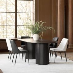 a dining room table with chairs and a potted plant on it in front of a window