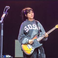 a woman standing next to a microphone holding a guitar