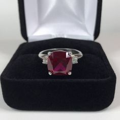 Beautiful Ruby & White Sapphire Ring * 5ct Cushion Cut Ruby measures 10mm * Brilliant Cut White Sapphire Accents measure 3mm each * 5.26cts total Gemstone weight * Beautiful Comfort Fit Shank * Solid Sterling Silver * Size 9.5 Hallmarked & Gift Ready! Matching Earrings can be found here https://www.etsy.com/listing/494099269/beautiful-cushion-cut-ruby-earrings Matching Pendant also Available! This 5ct Ruby is Laboratory Grown. It is identical to natural in every way, including Chemistry, Composi Ruby Ring Simple, Silver Solitaire Engagement Ring, Mens Ruby Ring, Silver Ruby Ring, Red Stone Ring, Trending Jewelry, Tanzanite Earrings, White Sapphire Ring, Fine Art Jewelry