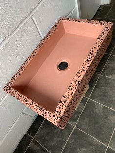 a pink sink sitting on top of a tiled floor