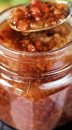 a jar filled with food sitting on top of a table next to a wooden spoon