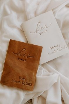 two personalized leather guest books laying on a white bed with the names of their guests