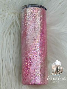 the pink glitter tumbler is sitting on a white fur