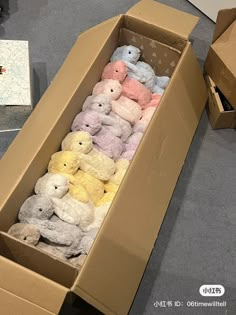 a box filled with lots of different colored teddy bears next to boxes on the floor