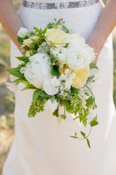 a bridal holding a bouquet of white and yellow flowers