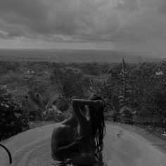 a woman sitting in a pool with her hair blowing back and looking out into the distance